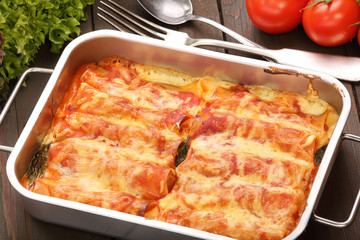 Cannelloni baked in a roasting pan on a wooden background