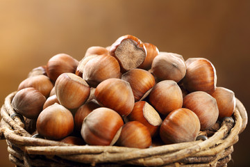 Wicker basket with walnuts on a brown background