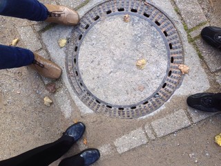 Drei Personen am Gullydeckel stehend