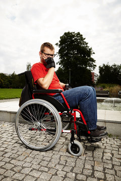 Young man on wheel chair - relaxing in park