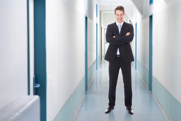 Fototapeta premium Businessman Standing Arms Crossed In Office Corridor