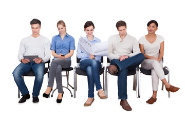 Businesspeople Doing Various Activities On Chairs