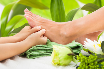 Masseuse Massaging Woman's Foot Against Leaves