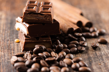 Chocolate bar and cofee beans on wooden table close up