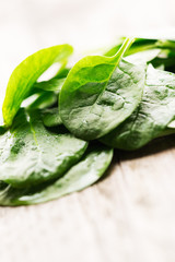 Heap of spinach leaves on wooden background angled view