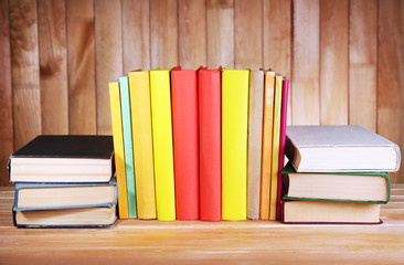 Books on wooden table on wooden wall background