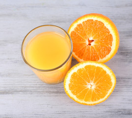 glass of juice with fresh orange on grey wooden table