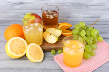 glasses of juice with fresh fruits on grey wooden table