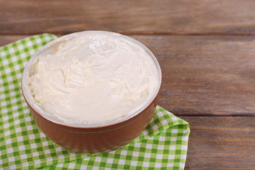 Fresh homemade butter in bowl, on wooden background