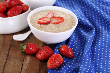 Tasty oatmeal with strawberry on table close-up