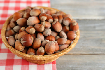 Hazelnuts in wicker basket on wooden background