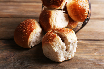 Tasty buns with sesame on color wooden background
