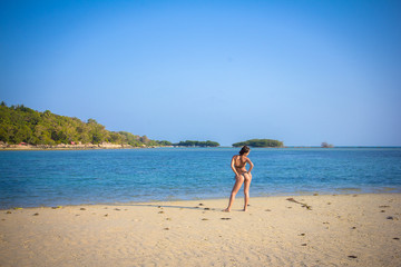 Fototapeta na wymiar Back of a woman standing on sand near sea