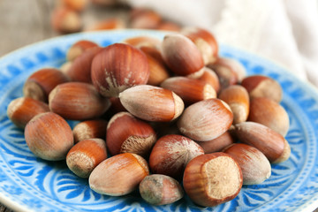 Hazelnuts on plate on wooden background