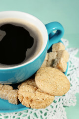 Glass cup of coffee and tasty cookie on color wooden background