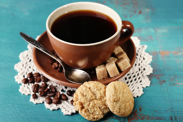 Glass cup of coffee and tasty cookie on color wooden background