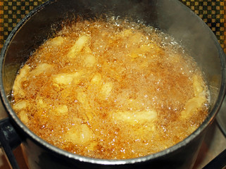 French fries cooking and bubbling in deep fryer filled with oil