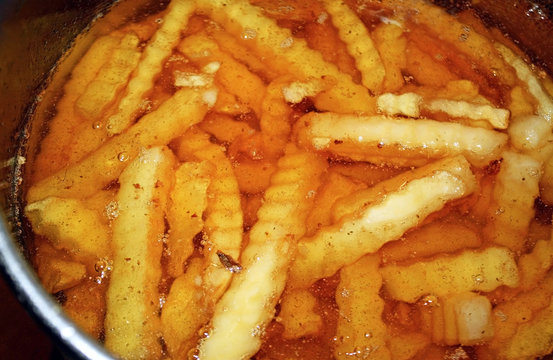 Crinkle cut french fries in deep fryer filled with oil