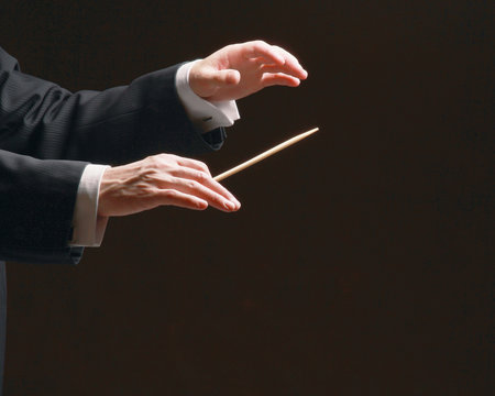 Concert conductor's hands with a baton, isolated on a black