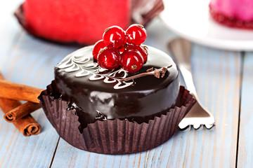 Chocolate cake with red currants on a wooden background