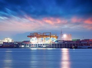 Naklejka premium Container ship in the harbor, night shot. Cloudy sky.
