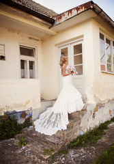 Blonde bride with veil by old house