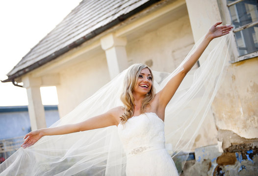 Blonde bride with veil by old house