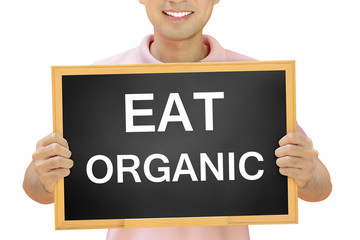 EAT ORGANIC text on blackboard held by smiling man