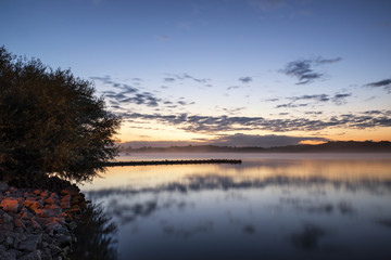 Naklejka na ściany i meble Sunrise vibrant landscape of jetty on calm lake