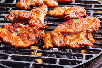 Grilling pork steaks on barbecue grill
