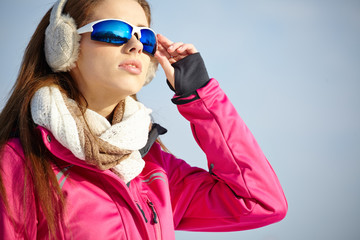Beautiful woman wearing goggles in snowy winter outdoors