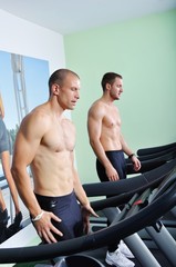 Fototapeta na wymiar Two handsome men in gym running on the ergometer