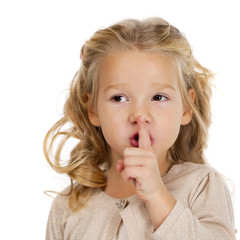 Fototapeta premium Little girl has put forefinger to lips as sign of silence