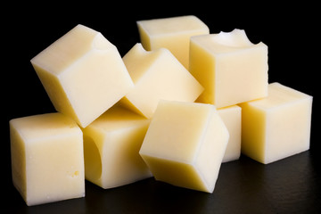 Yellow cheese cubes on black surface.