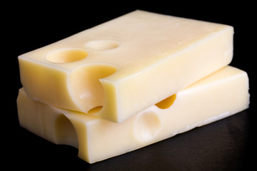 Block of cut yellow cheese on black surface.