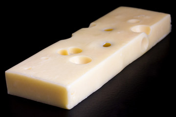 Block of yellow cheese on black surface.