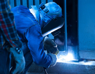 Welder repairing the metal fence