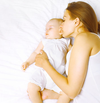Mother together with baby sleeps in bed