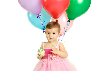 Fototapeta na wymiar Cute One Year Baby Girl with Birthday Balloons and a Cupcake
