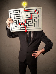 Businessman holding a paper with a labyrinth on it in front of h