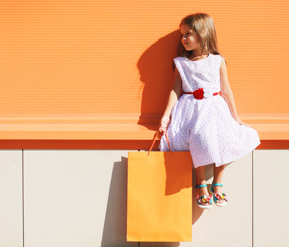 Street fashion kid, pretty little girl in dress with shopping ba