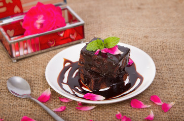 Chocolate brownie on plate with rose petals