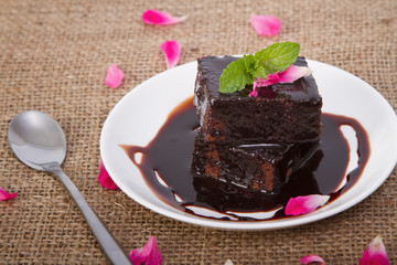 Chocolate brownie on plate with rose petals