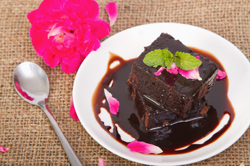Chocolate brownie on plate with rose petals