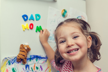 child forms mom dad words on refrigerator