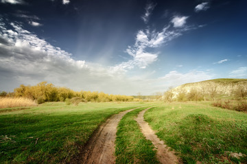 Fototapeta na wymiar vinage road through fields with green grass and blue sky with cl
