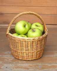 Ripe green apples in wicker basket closeup