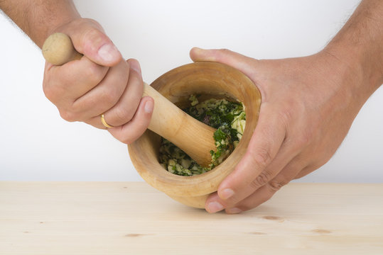 Cocinero preparando un majado de ajo y perejil en el mortero
