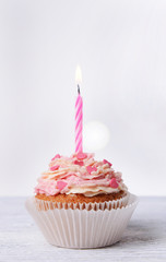 Delicious birthday cupcake on table on white background
