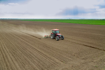 Obraz premium Farmer sowing crops at field with tractor